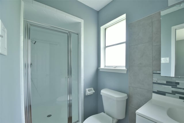 bathroom featuring an enclosed shower, vanity, toilet, and decorative backsplash