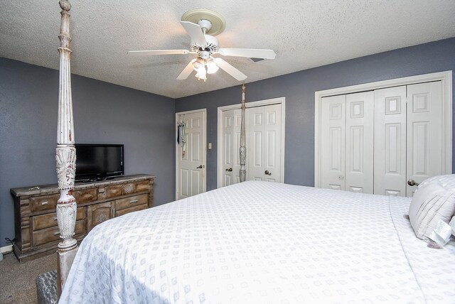 bedroom with a textured ceiling, ceiling fan, carpet flooring, and multiple closets