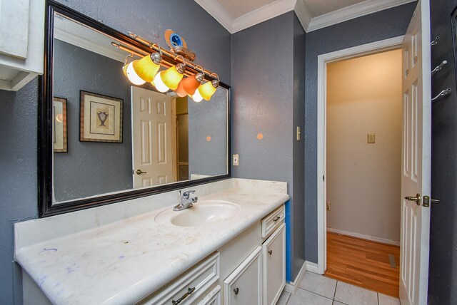 bathroom with tile patterned flooring, crown molding, vanity, and baseboards