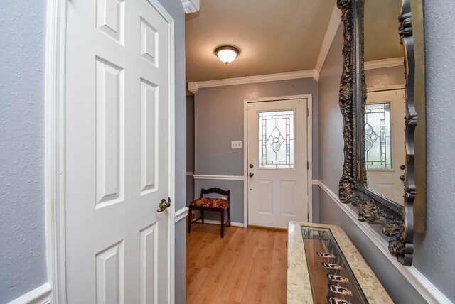 foyer entrance with crown molding, light wood-style flooring, and baseboards