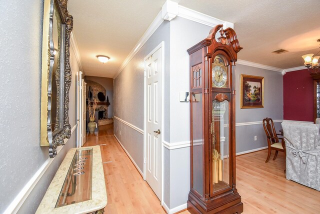 hallway with light wood finished floors, ornamental molding, and a chandelier