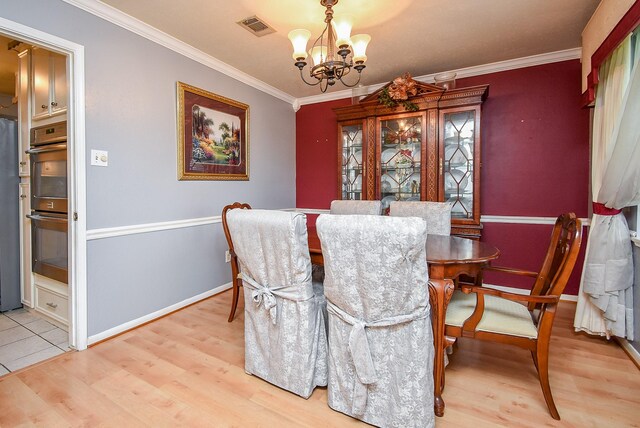 dining area featuring crown molding, a notable chandelier, visible vents, light wood-style floors, and baseboards