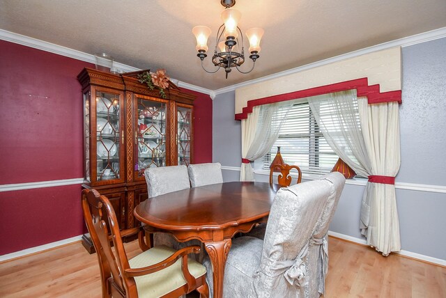 dining room featuring a chandelier, ornamental molding, baseboards, and light wood-style floors