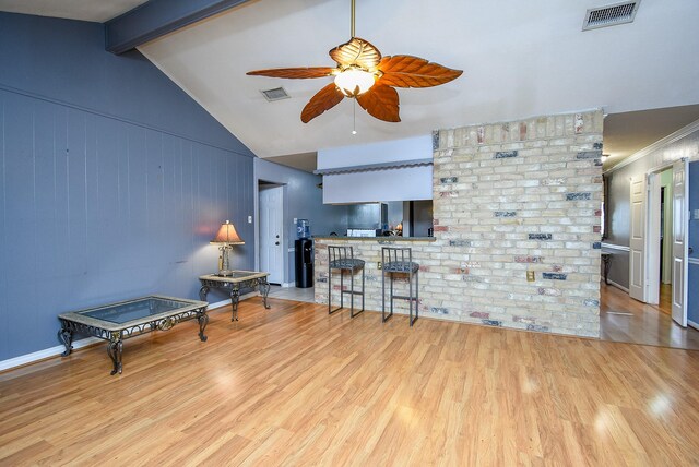 interior space featuring vaulted ceiling with beams, ceiling fan, light wood-type flooring, and visible vents