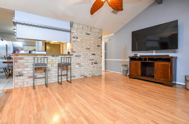 unfurnished living room featuring ceiling fan, visible vents, baseboards, vaulted ceiling, and light wood-type flooring