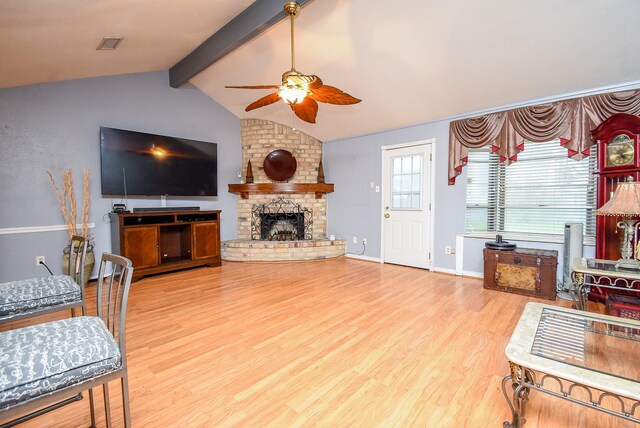 living room featuring lofted ceiling with beams, light wood-style flooring, a fireplace, visible vents, and a ceiling fan