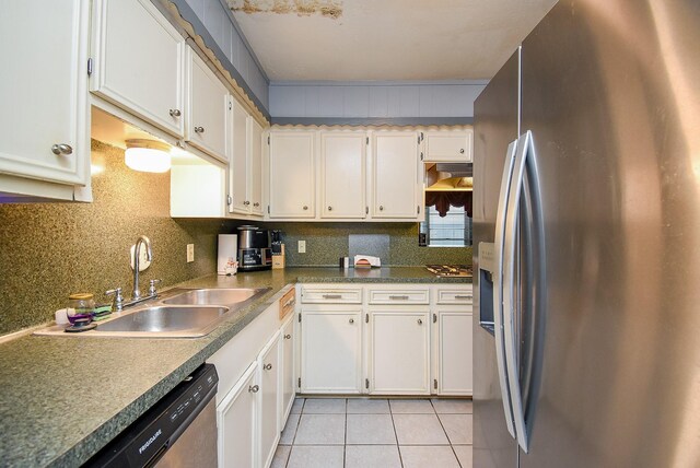 kitchen featuring light tile patterned floors, a sink, white cabinets, appliances with stainless steel finishes, and backsplash