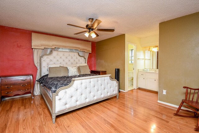 bedroom with light wood-style floors, a ceiling fan, connected bathroom, a textured ceiling, and baseboards