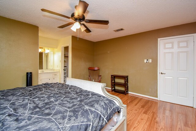 bedroom featuring light wood finished floors, visible vents, a ceiling fan, a textured ceiling, and baseboards