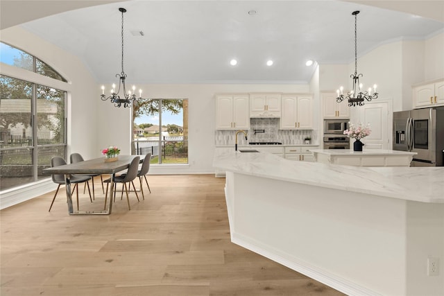 kitchen featuring light stone countertops, decorative backsplash, pendant lighting, and stainless steel appliances