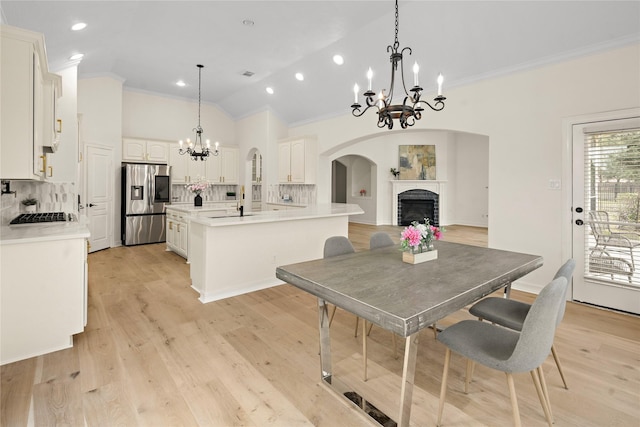 dining area featuring a notable chandelier, ornamental molding, light hardwood / wood-style flooring, and vaulted ceiling