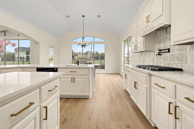 kitchen featuring light stone countertops, tasteful backsplash, stainless steel gas cooktop, a notable chandelier, and white cabinets