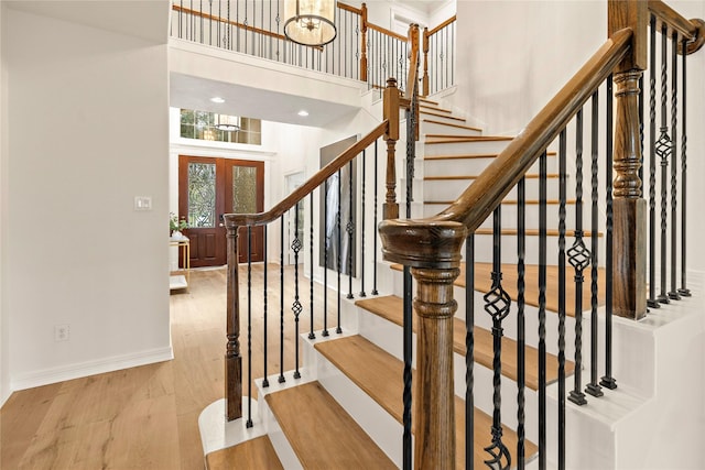 stairs featuring french doors, a towering ceiling, and wood-type flooring