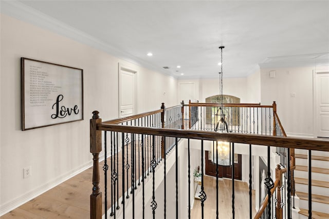 hall with crown molding, hardwood / wood-style floors, and a notable chandelier