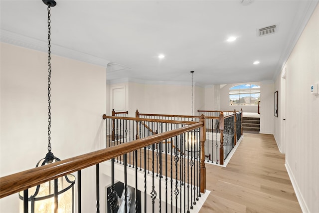 corridor with light hardwood / wood-style floors and ornamental molding