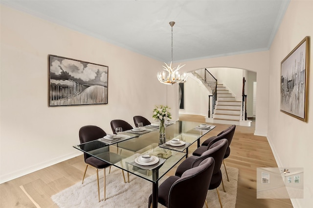 dining area with wood-type flooring, ornamental molding, and a chandelier