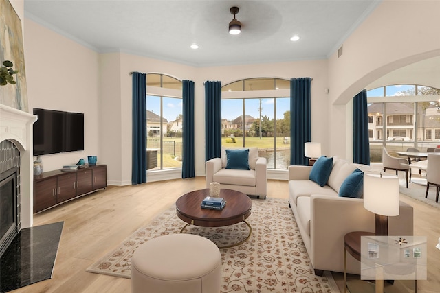 living room featuring a healthy amount of sunlight, light hardwood / wood-style floors, crown molding, and a premium fireplace