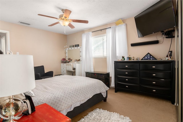 carpeted bedroom with ceiling fan and a textured ceiling