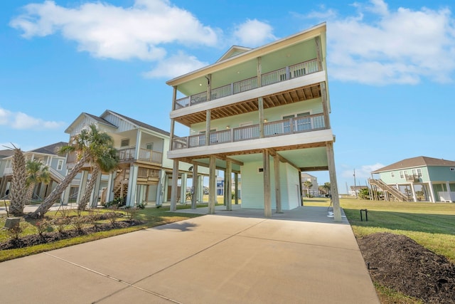 coastal inspired home featuring a front lawn, a balcony, and a carport