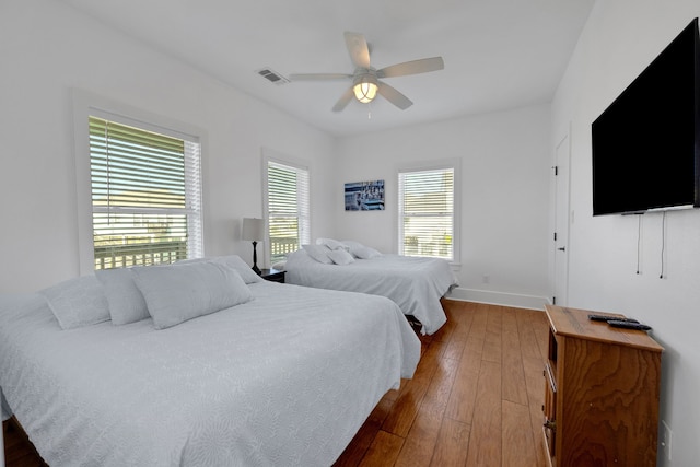 bedroom featuring multiple windows, ceiling fan, and dark wood-type flooring