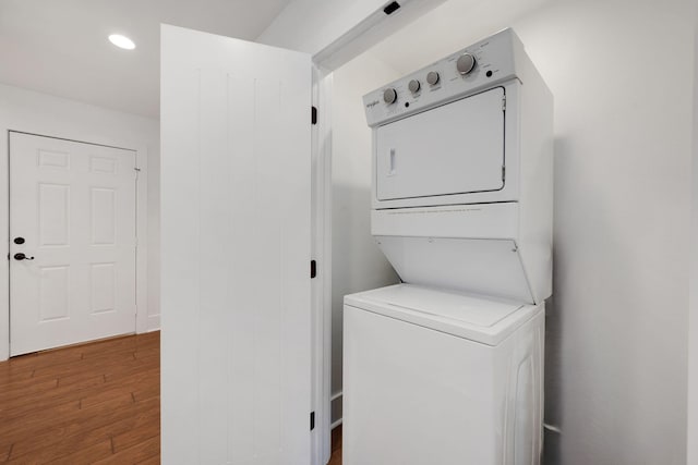 clothes washing area featuring stacked washer / dryer and hardwood / wood-style flooring