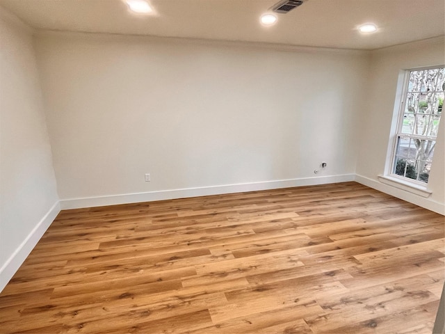 empty room with crown molding and light hardwood / wood-style floors