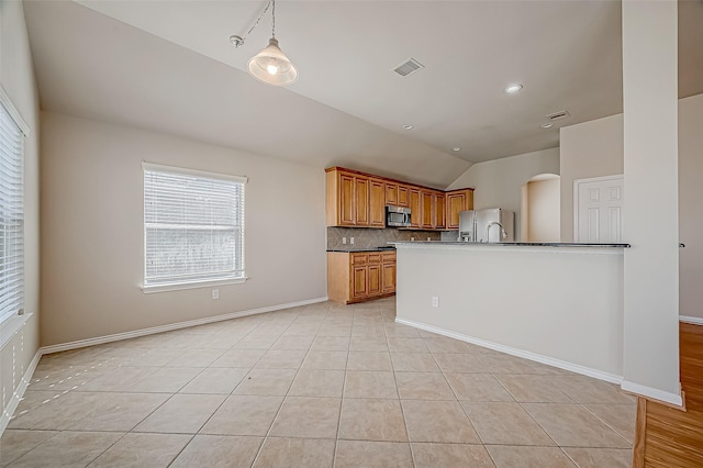 kitchen featuring appliances with stainless steel finishes, tasteful backsplash, vaulted ceiling, light tile patterned floors, and hanging light fixtures