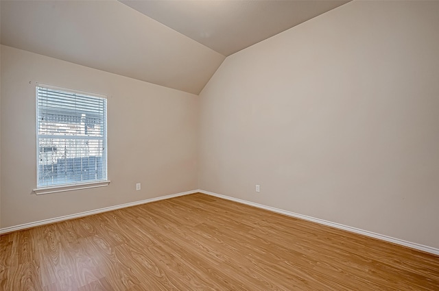 empty room featuring vaulted ceiling and light wood-type flooring