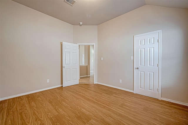 unfurnished bedroom with lofted ceiling and light wood-type flooring