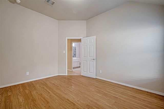 spare room featuring lofted ceiling and light hardwood / wood-style flooring