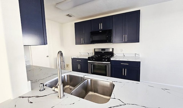 kitchen with gas stove, light stone counters, and sink