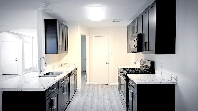 kitchen featuring light stone counters, sink, light hardwood / wood-style floors, and stainless steel range with gas stovetop