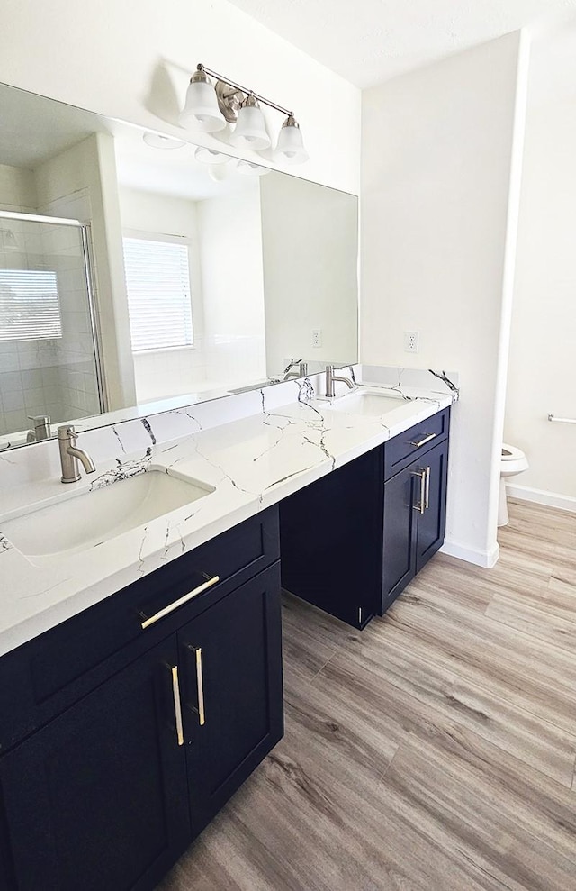 bathroom with toilet, vanity, a shower with shower door, and hardwood / wood-style flooring