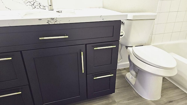 bathroom featuring hardwood / wood-style floors, toilet, and a tub to relax in