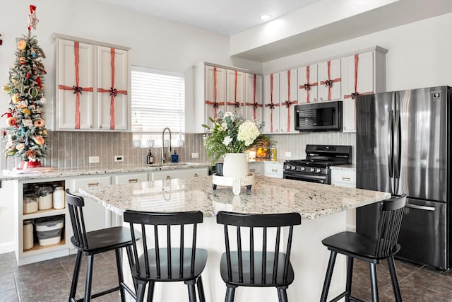 kitchen featuring sink, black appliances, a center island, and tasteful backsplash