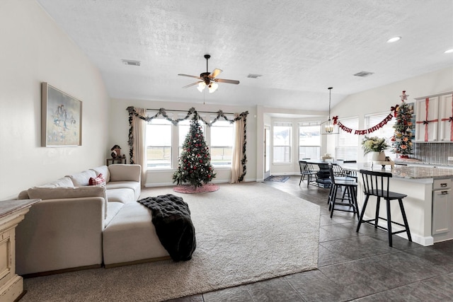 living room featuring ceiling fan with notable chandelier, a textured ceiling, and vaulted ceiling