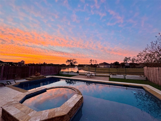 pool at dusk with an in ground hot tub