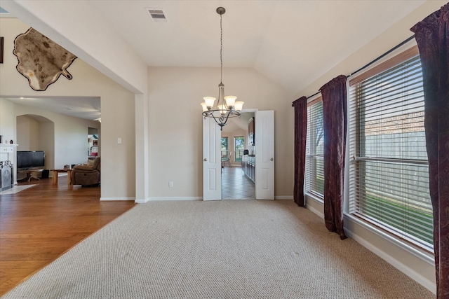 spare room with a chandelier, wood-type flooring, and vaulted ceiling