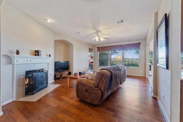 living room with a tile fireplace, ceiling fan, and hardwood / wood-style floors