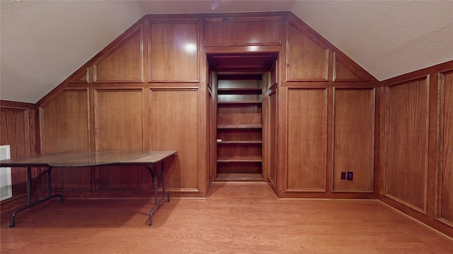 walk in closet with light wood-type flooring and vaulted ceiling