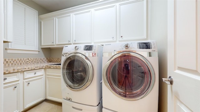 laundry area featuring cabinets, separate washer and dryer, and light tile patterned floors