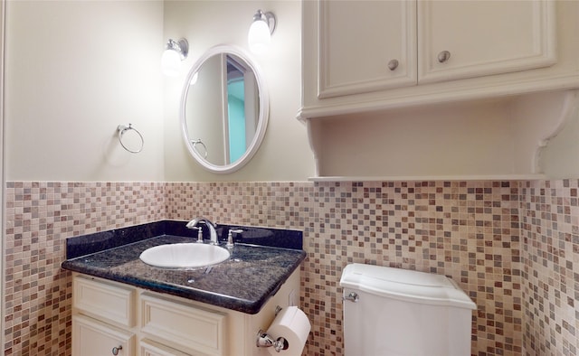 bathroom featuring vanity, toilet, and tile walls