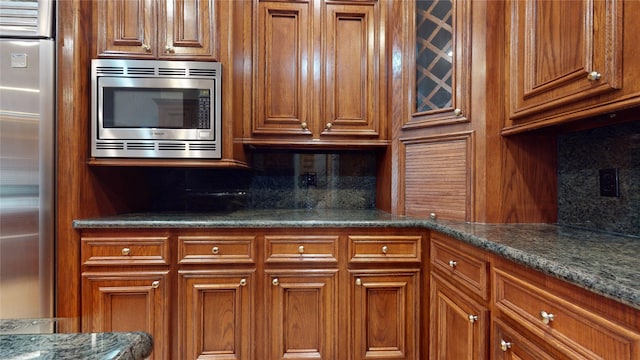 kitchen with dark stone countertops, appliances with stainless steel finishes, and tasteful backsplash