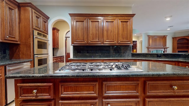 kitchen featuring a center island, dark stone counters, ornamental molding, appliances with stainless steel finishes, and tasteful backsplash