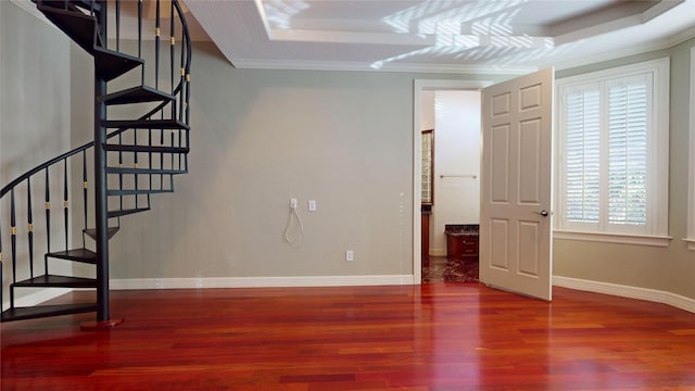 interior space with a raised ceiling, hardwood / wood-style flooring, and ornamental molding