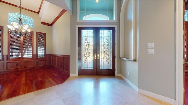 entrance foyer with an inviting chandelier, ornamental molding, and french doors