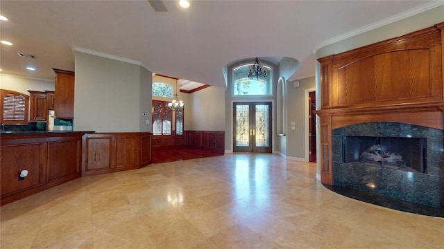 entrance foyer featuring a tiled fireplace, french doors, a notable chandelier, and ornamental molding