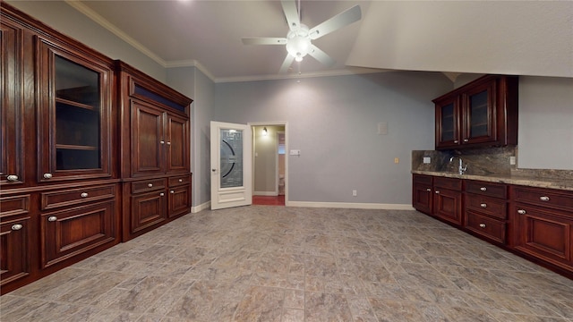 kitchen with light stone countertops, sink, ceiling fan, decorative backsplash, and ornamental molding