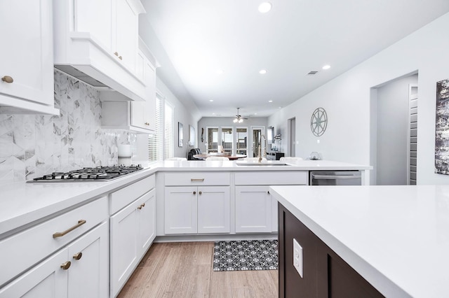 kitchen with stainless steel appliances, decorative backsplash, light wood-type flooring, white cabinetry, and sink