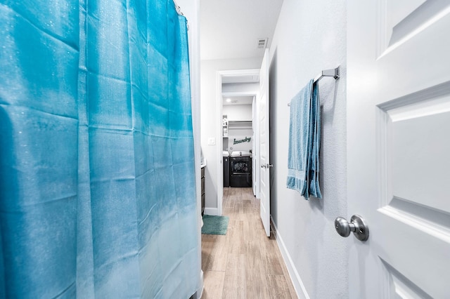 hallway with washer and dryer and light wood-type flooring